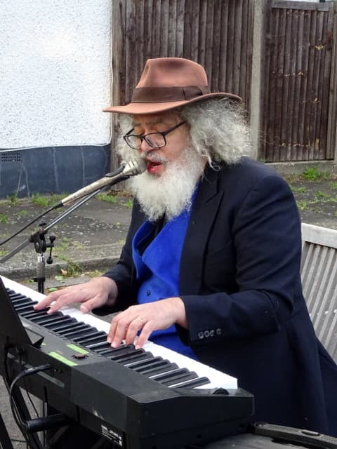 a bearded man in a hat playing a keyboard